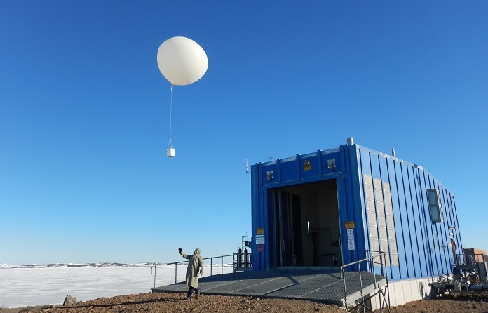 Person launching large white weather balloon at Davis Station